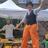 Ein Mann auf Stelzen und ein Marktstand.