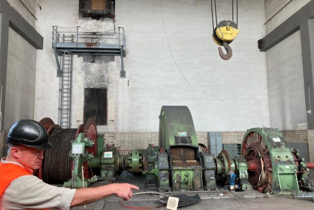 Ein Bergmann zeigt auf eine alte Fördermaschine auf einer Zeche in Marl.