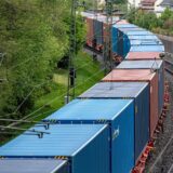 Ein Güterzug mit vielen Containern fährt über Bahnschienen.