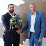 Andreas Schlüter schüttelt Niklas Karwath (l). die Hand. Niklas Karwath hält einen Blumenstrauß.