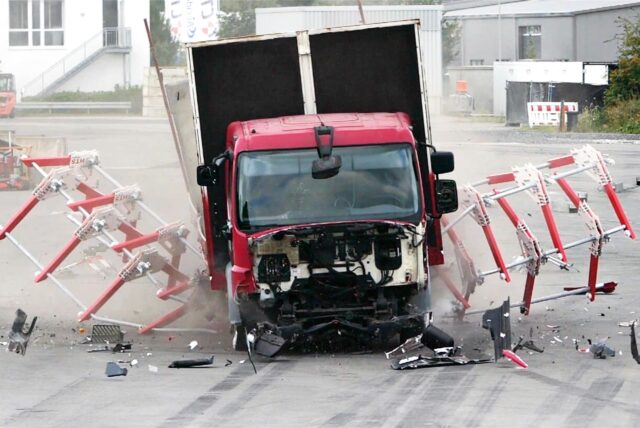 Ein Lkw beim Crashtest auf eine Reihe rot-weißer Sperr-Elemente.