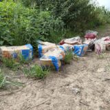 Auf einer unbefestigten Fläche ist eine illegale Müllablagerung von mehreren verpackten Broten zu sehen. Die Brote sind unterschiedlicher Sorten und liegen zwischen Gras und Büschen.