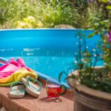 Blick auf einen Pool mit Badehandtuch, Getränke und Badeschlappen.
