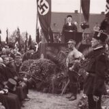 Hakenkreuzfahnen säumen die Trauerfeier für die verunglückten Bergleute 1935 in Mengede. An einem Rednerpult steht Dr. Albrecht Stenger, seinerzeit Pfarrer der evangelischen Remigiusgemeinde.