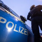 Ein Polizist steht vor einem Streifenwagen.