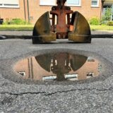 Das Loch ist Asphalt ist mit Wasser gefüllt, aber etwa fünf Zentimeter tief.