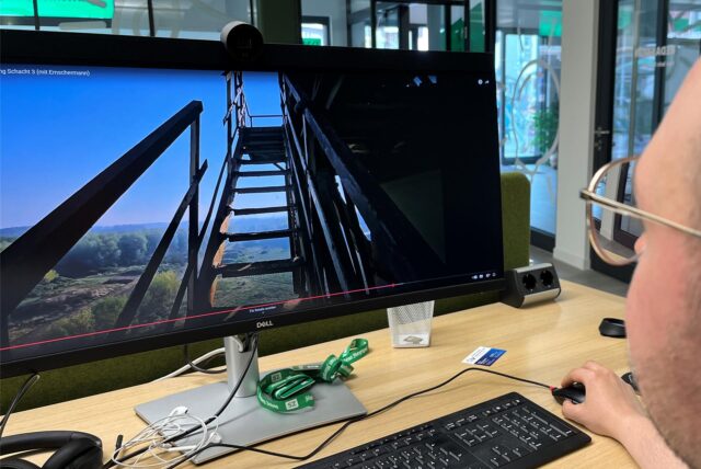 Ein Mann sitzt vor einem Computer und bedient die Maus. Auf dem Bildschirm ist ein Video zu sehen, das eine Treppe zeigt.