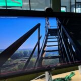 Ein Mann sitzt vor einem Computer und bedient die Maus. Auf dem Bildschirm ist ein Video zu sehen, das eine Treppe zeigt.