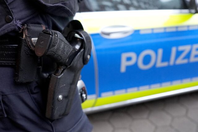 Ein Polizist steht vor einem Einsatzfahrzeug der Polizei.
