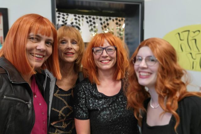 Fotos von der Verabschiedung von Helke Waterfeld (zweite von links), der Schulleiterin des Freiherr-vom-Stein-Gymnasiums in Recklinghausen, im Juli 2025. Auf diesem Foto sieht man Waterfeld mit drei Kolleginnen, die rote Perücken tragen.