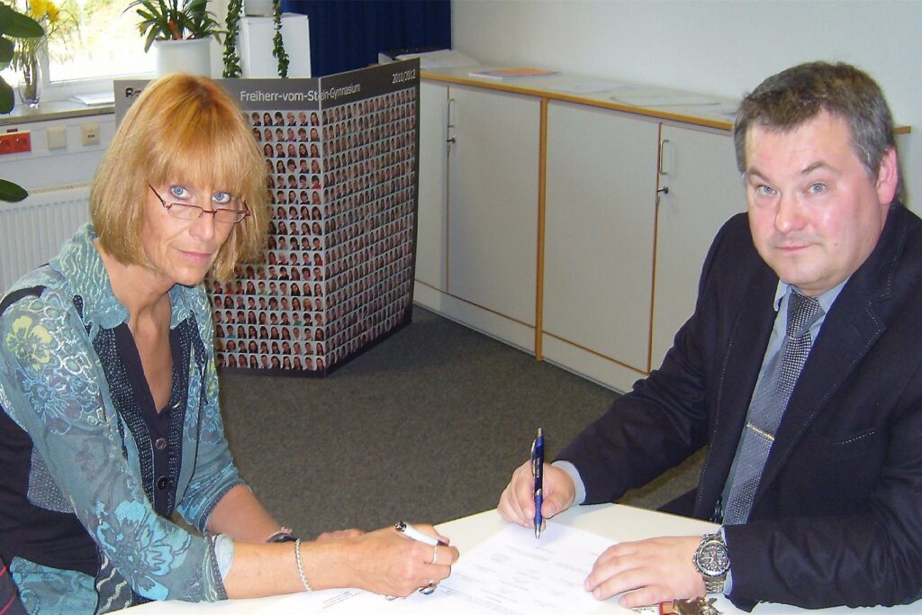 Ganz locker geben sich Helke Waterfeld und Thomas Bassek (Ausbildungsleiter am Hella-Standort Recklinghausen) bei der Unterzeichnung einer Kooperationsvereinbarung im Jahr 2013.