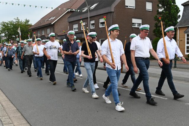 Schützen marschieren mit Holzgewehren auf einer Straße