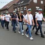 Schützen marschieren mit Holzgewehren auf einer Straße