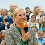 Andrea Kiewel, Moderatorin des „ZDF-Fernsehgartens“ bei einer Sendung. Sie hält ein Mikrofon des ZDF in der Hand.