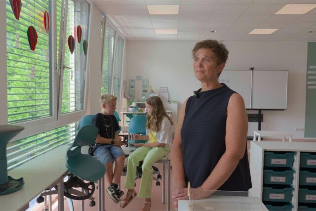 Tanja Fuhrmann, Rektorin der Gudrun-Pausewang-Grundschule in Recklinghausen-Süd, steht in einem der Klassenzimmer im Neubau an der Heinrichstraße. Im Hintergrund sind zwei Schüler zu sehen.