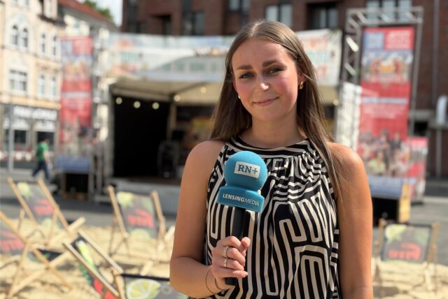 Reporterin der Ruhr Nachrichten mit Mikrofon beim Street Food und Beach Festival „Castrop Karibisch“ in Castrop-Rauxel, im Hintergrund Strandbereich und Bühne.