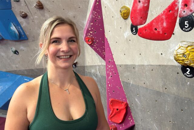 Caterina Szmania neben bunten Griffen in der Einstein-Boulderhalle