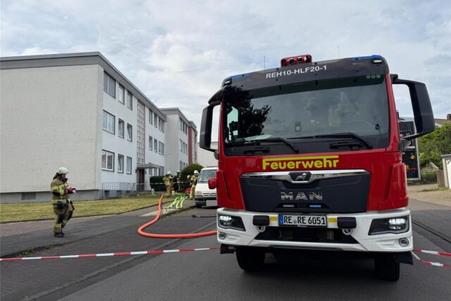 Kräfte der Feuerwehr Recklinghausen rollen Schläuche vor einem Mehrfamilienhaus an der Rügenstraße aus