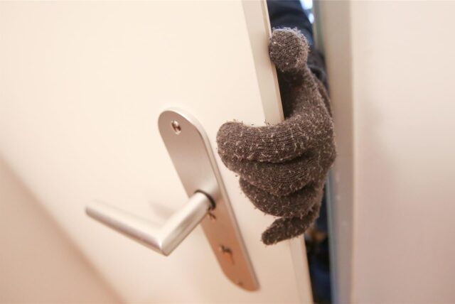 Eine Person, die Stoffhandschuhe trägt, betritt eine fremde Wohnung