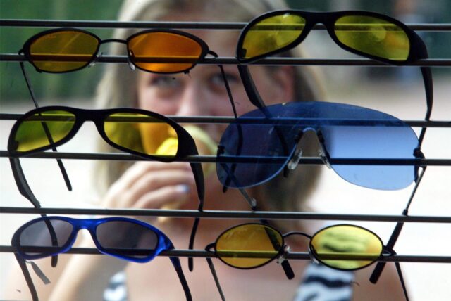 Junge Frau betrachtet Sonnenbrillen in einem Schaufenster.