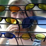 Junge Frau betrachtet Sonnenbrillen in einem Schaufenster.